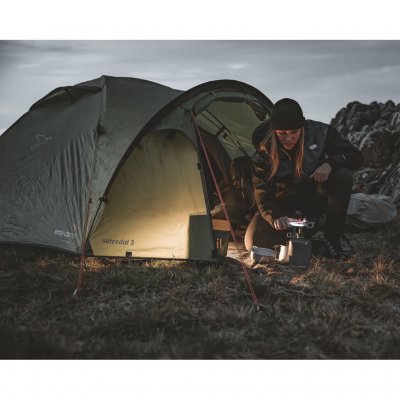 Setesdal 2 dome tents in a natural environment, one person cooking in front of the tent in the dark with a cozy atmosphere.